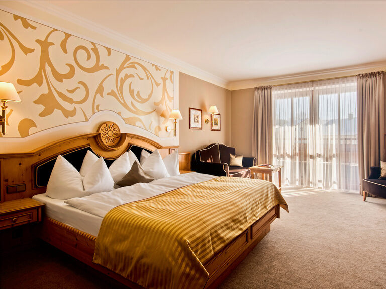 Doppelzimmer Landgold im Hotel Oswald mit kunstvoller Wandgestaltung, hochwertigem Holzbett und luxuriösen Details.
