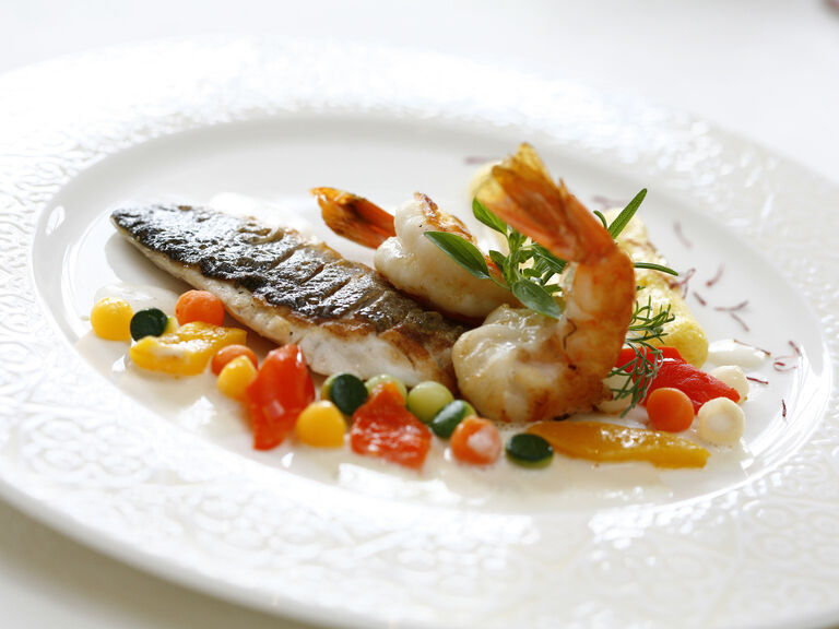 Kunstvolle Präsentation von Meeresfrüchten mit Gemüse auf einem weißen Teller von dem Restaurant im Hotel Mooshof in Bodenmais.
