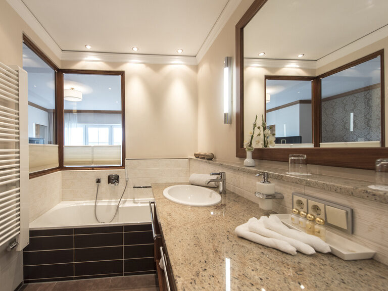 Modernes Badezimmerdesign mit rundem Waschbecken und großer Badeewanne in der Gartensuite Schwalbennest des Hotels Mooshof in Bayern.