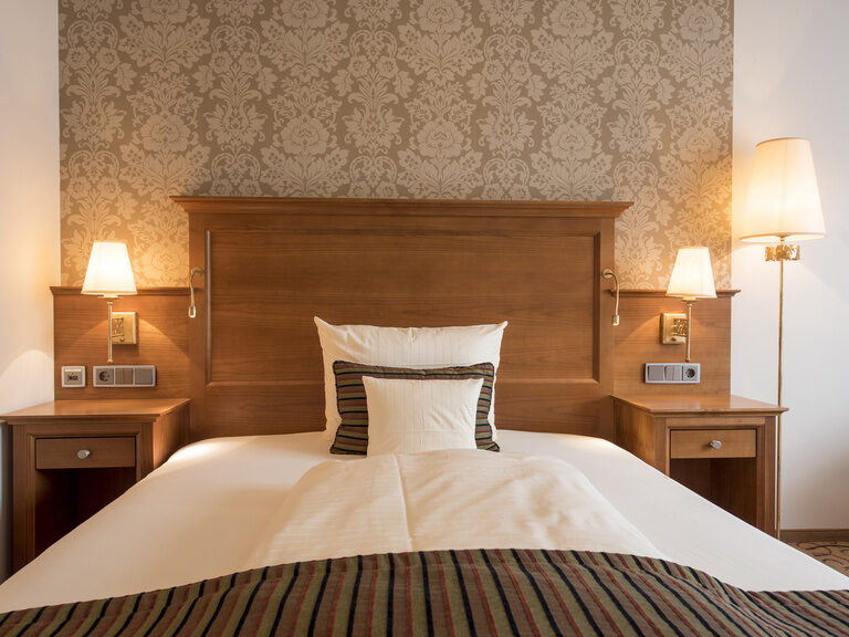 Das gemütliche Single-Suite Bett bei sanftem Lampenlicht für eine entspannende Atmosphäre im Wellnesshotel Mooshof im Bayerischen Wald.