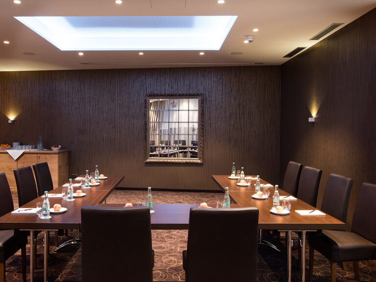 Der Meetingraum im Hotel Oswald mit stilvollem Ambiente, dunklen Holztischen und bequemen Stühlen für produktive Besprechungen im Bayerischen Wald.